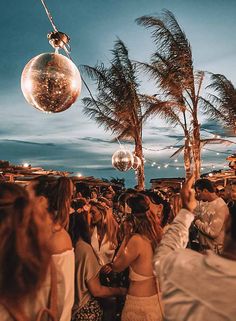 a group of people standing next to each other at a party with disco balls hanging from the ceiling