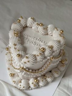 a white cake decorated with gold beads and pearls