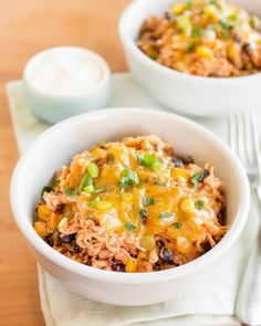 slow cooker chicken burrito bowls in white bowls on a wooden table with utensils