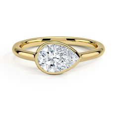 a yellow gold engagement ring with a pear shaped diamond in the center, on a white background