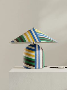 a multicolored lamp sitting on top of a white table next to a wall