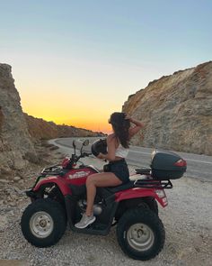 a woman riding on the back of a red four wheeler