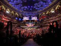 an audience in a large auditorium with balloons hanging from the ceiling