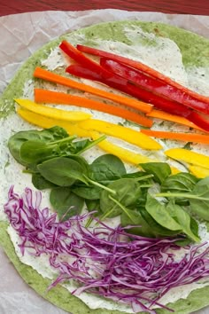 rainbow colored vegetables are on top of a tortilla