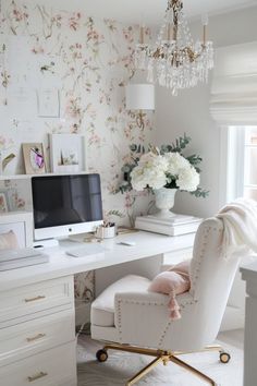 a white chair sitting in front of a desk with a computer on top of it