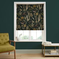 a living room with green walls and a window covered in floral print roman shades, along with a yellow chair