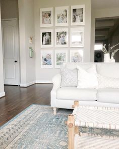 a living room filled with white furniture and pictures on the wall above it's fireplace