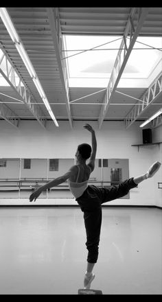 a woman is doing a ballet move in an empty room with no one on the floor