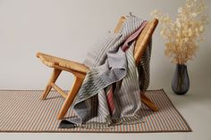 a chair with a blanket on it next to a vase