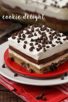 a piece of cake on a plate with chocolate chips and white frosting in the middle