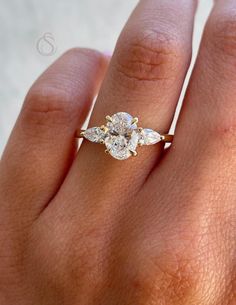 a woman's hand with a diamond ring on top of her finger and an engagement band