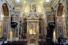 the inside of a church with pews and paintings on the walls, along with an ornate alter