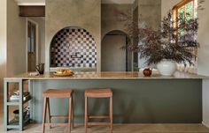 two stools are sitting at the bar in this kitchen