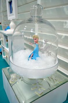 a snow globe with a frozen princess figure in it on top of a shelf filled with bubbles