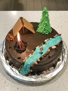 a chocolate cake with blue frosting and a lit candle on top is sitting on a table