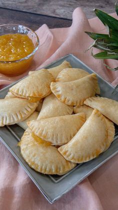 some food is sitting on a plate and next to a bowl of orange sauces