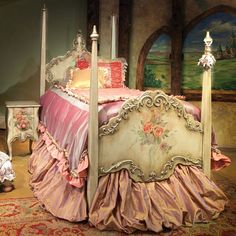 a bed with pink and gold bedspread in a bedroom next to a painting