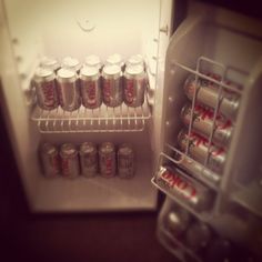 an open refrigerator filled with lots of sodas next to a freezer full of cans