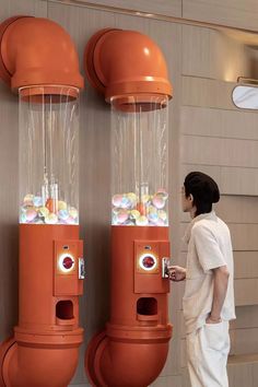 a woman standing in front of an orange vending machine with lots of gumballs on it