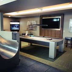 a pool table in the middle of a room with a tv and slide down stairs