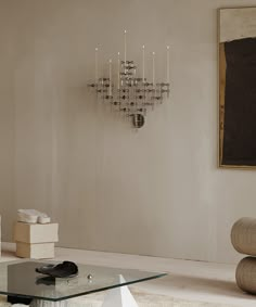 a living room with a glass coffee table in the middle and a chandelier on the wall