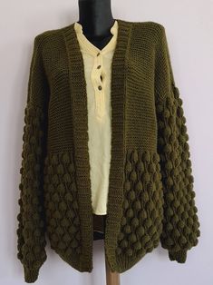 a green knitted cardigan sweater hanging on a mannequin's dummy