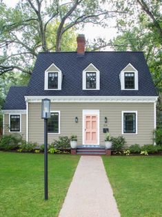 a gray house with two windows and a pink door on the front porch is shown