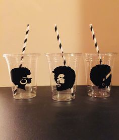 three glasses with black and white striped straws in them, one has a man's face on it