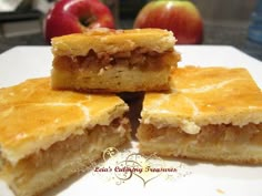 four pieces of cake sitting on top of a white plate next to an apple and another piece of fruit