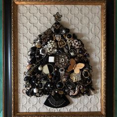 a christmas tree made out of buttons and other items in a gold frame on a wall