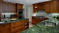 a kitchen with green marble counter tops and wooden cabinets, along with stainless steel appliances