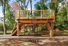 a wooden play structure in the middle of a park