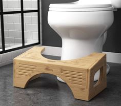 a white toilet sitting on top of a bathroom floor next to a wooden step stool