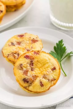 two muffins sitting on top of a white plate next to a sprig of parsley