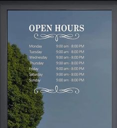 an open hours sign in front of a tree