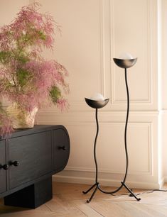 two black metal candlesticks stand next to a potted plant