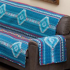 a couch covered in a blue and red blanket sitting on top of a hard wood floor