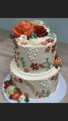 three tiered cake decorated with flowers and pearls on a white plate sitting on a wooden table