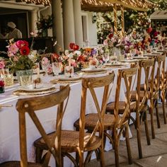 a long table is set up with flowers and candles for an outdoor wedding reception in the sun