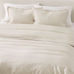 an unmade bed with white sheets and pillows