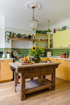 a wooden table sitting inside of a kitchen next to yellow cupboards and cabinets with sunflowers on top