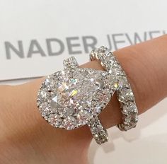 a close up of a person's hand wearing a ring with diamonds on it