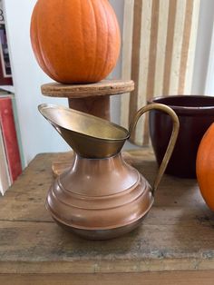 two pumpkins sitting on top of a table next to a coffee pot and saucer