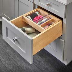 an open drawer in the middle of a kitchen with gray cabinets and drawers on both sides