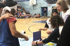 a group of people standing around a table with a game on it's side