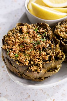 an eggplant stuffed with bread crumbs and lemon wedges on a plate