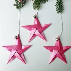 three pink origami stars hanging from a christmas tree