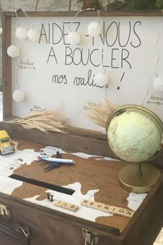 an old trunk with writing on it sitting next to a globe and some other items