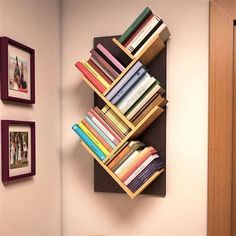 there is a book shelf with many books on it and two pictures hanging on the wall