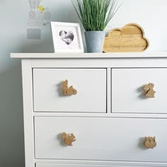 a white dresser with two drawers and a potted plant sitting on top of it